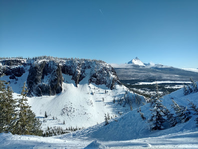 View of Hoodoo Ski Area in Sisters, Oregon, featuring a bustling ski resort amidst a picturesque winter sports scene. The snow-covered mountain serves as a backdrop to a charming challet and stunning winter scenery.