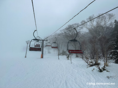 Winter scenery at Shiga Kogen Nishitateyama Ski Area in Japan, featuring a ski lift against a backdrop of snow-covered slopes bustling with winter sports enthusiasts.