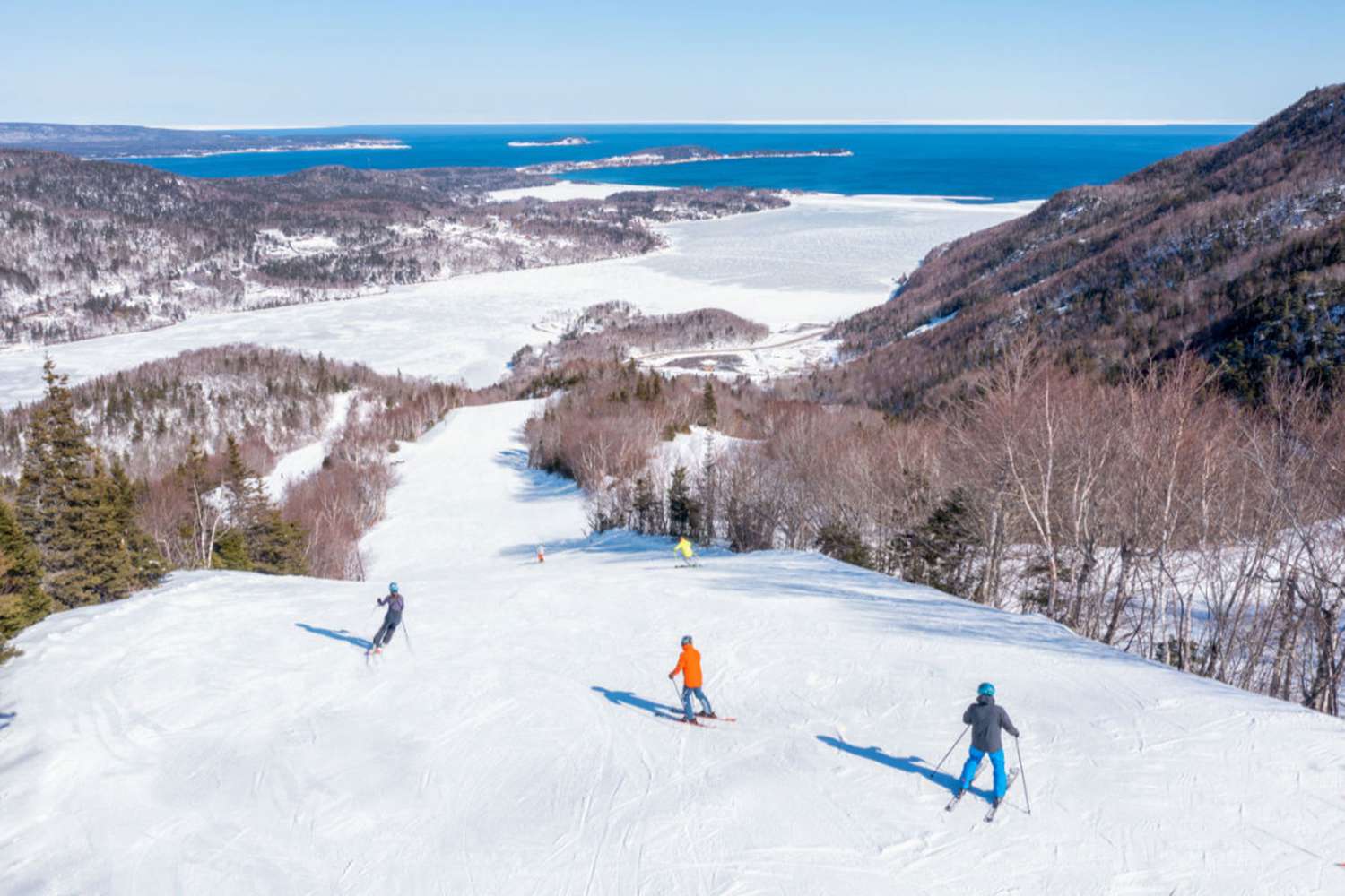Ski Cape Smokey in Canada - two people skiing down a mountain with the ocean in the background.