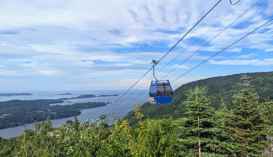 Ski Cape Smokey, Nova Scotia features a ski lift ascending a snow-covered mountain. A chalet is barely visible in the distance, hinting at the presence of a ski resort. There's no clear sight of skiers on the slopes.