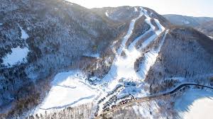 Ski slope scene at Ski Cape Smokey, Ingonish Beach, Nova Scotia showing a bustling ski resort, people enjoying winter sports, a charming chalet nestled in snow-covered slopes amidst beautiful winter scenery.