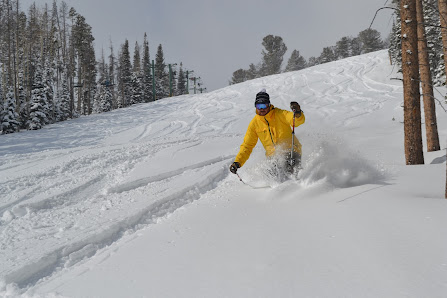 A skier is enjoying a thrilling ride downhill at the Snowy Range in Centennial Wyoming one of America's popular winter sports destinations. Other outdoor enthusiasts are also visible in the snow-laden landscape.