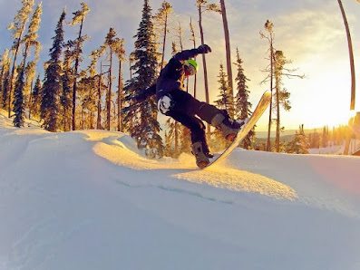 A snowboarder gliding down the gentle slopes of Blacktail Mountain in Lakeside Montana covered in white snow under the clear blue sky.