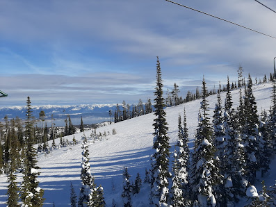 A view of Blacktail Mountain Ski Resort in Lakeside Montana showcasing a ski lift ascending snow-covered slopes with a skier enjoying the winter sports scene.