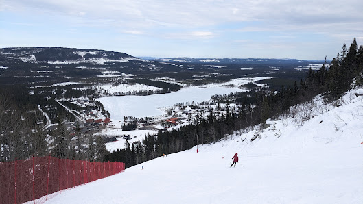 A skier gliding down the slopes at Klövsjö-Storhogna ski area in Northern Sweden, surrounded by quiet winter scenery characteristic of Swedish ski resorts.