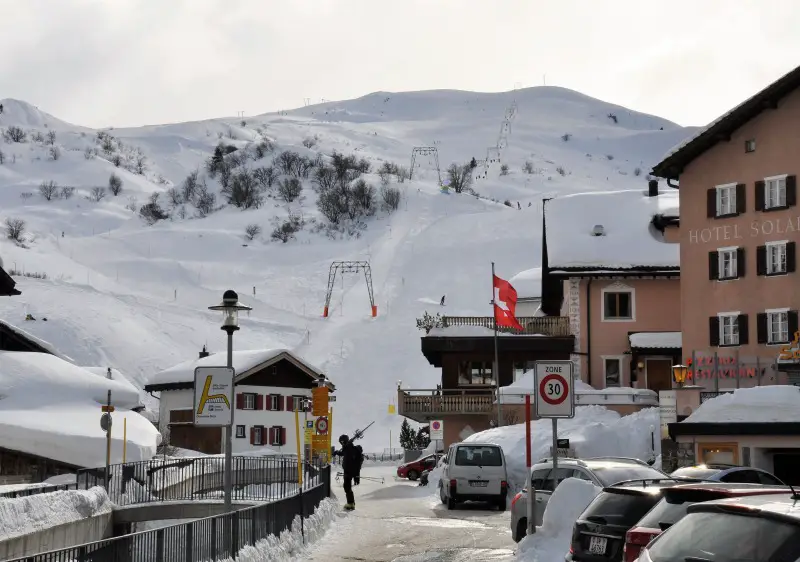 A picturesque view of Bivio ski resort in Eastern Switzerland, vividly illustrating a bustling winter sports scene. Notable features include a cosy chalet, set against a majestic winter backdrop.