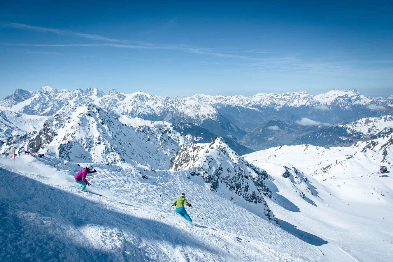 4 Vallees | Verbier in Switzerland - a group of people skiing down a snowy mountain.