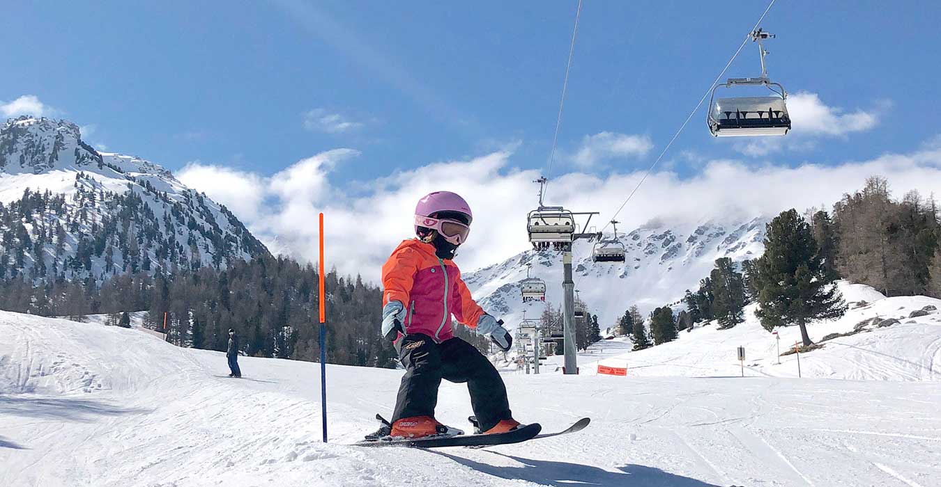4 Vallees | Verbier in Switzerland - a woman riding a snowboard down a snow covered slope.