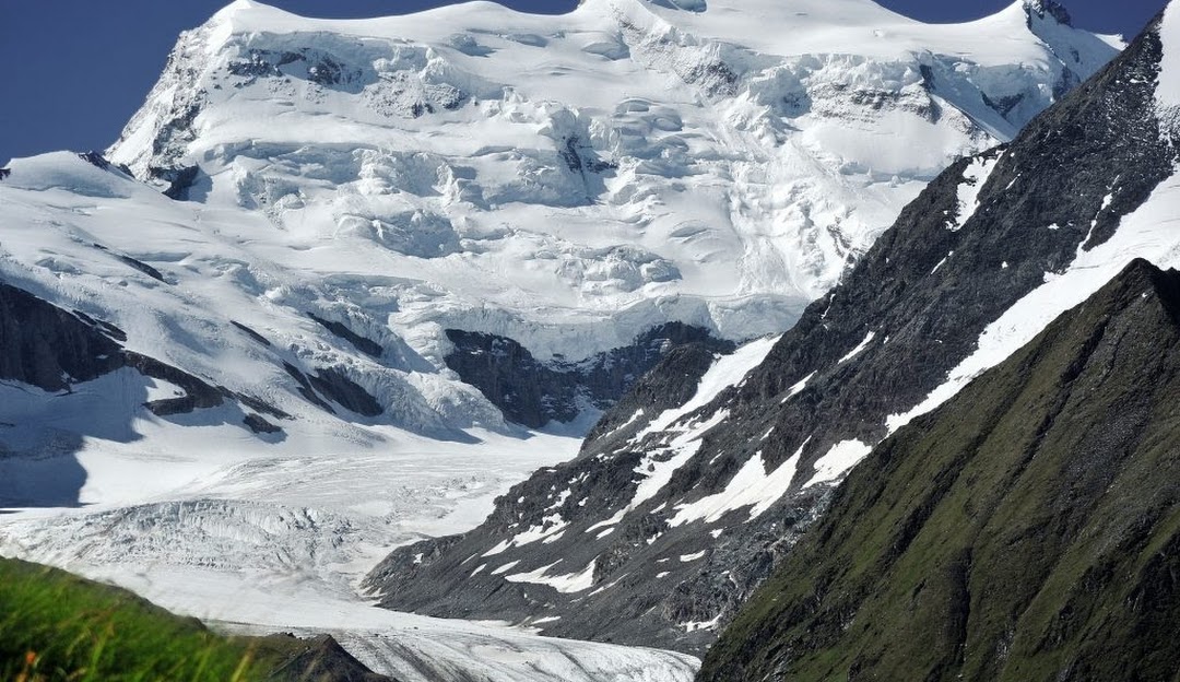 4 Vallees | Verbier in Switzerland - a large mountain covered in snow and grass.