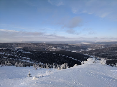 Ski enthusiasts enjoying winter sports at Ski Land Mt Aurora, Fairbanks, Alaska. The scene is set against the backdrop of a beautiful snow-covered mountain and a ski lift.