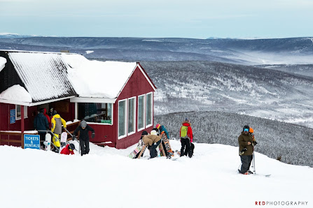 Winter sports enthusiasts enjoying the course at Ski Land Mt Aurora in Fairbanks, Alaska, with a mountain hut set against a stunning winter landscape in the background.