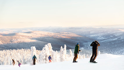 Winter sports enthusiasts enjoying a day of skiing at Ski Land Mt Aurora, a picturesque ski resort in Fairbanks, Alaska. A stunning winter landscape is visible in the background.