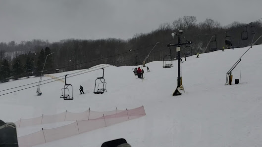 A wintertime view of Labrador Mountain ski resort in Truxton New York featuring a ski lift carrying skiers up the snow-dusted slope ready for their snowy descent.