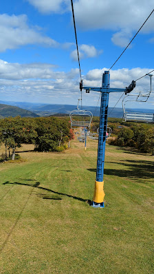 Ski lift ascending at Blue Knob in Claysburg, Pennsylvania amidst a sunny day at the ski resort, with a skier enjoying the winter sports scene.