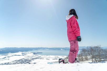 A snowboarder navigating down the smooth, snowy slopes of Grand Sunpia Inawashiro Snow Paradise in Yama District, Fukushima, Japan during the chill winter season.