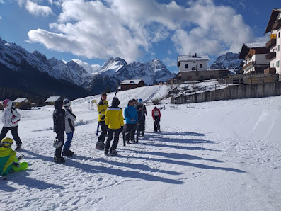 A lively winter scene in Sappada Italy with skiers in action amidst snow-clad slopes complete with a picturesque chalet and ski resort facilities.