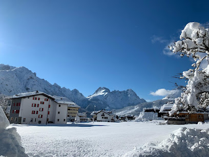 Ski resort scene at Sappada in Udine, Italy, showcasing a winter sports centre, classic chalet, and enchanting winter scenery with snow-covered slopes - a perfect destination for winter sports.