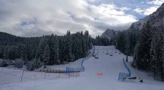 A vibrant winter sports scene at the Sappada ski resort in Italy showcasing the snow-covered slopes with a skier in motion.