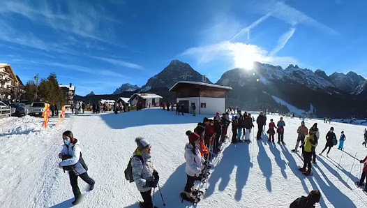 Winter sports scene at Sappada in Udine, Italy, showcasing a bustling ski resort with people enjoyably skiing. A charming challet overlooks the snowy landscape.