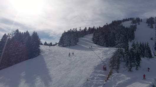 Winter sports scene at a ski resort in Mourtis, France, showcasing a charming chalet, a bustling winter sports centre, and a ski lift against a snowy backdrop.