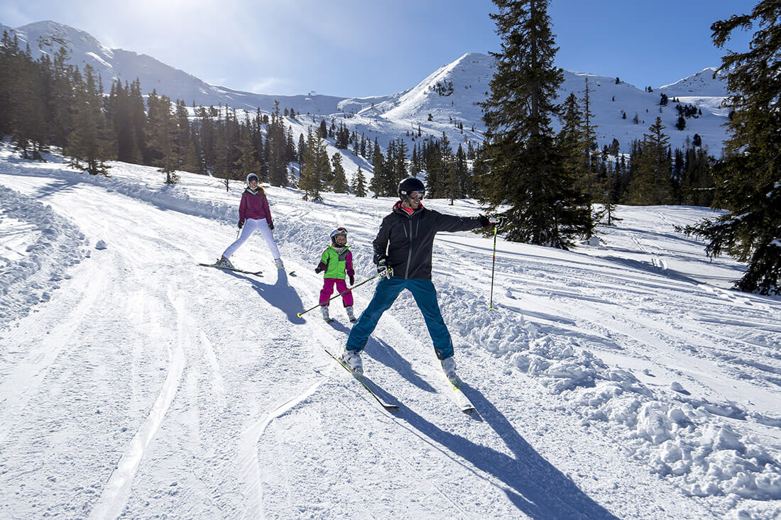 A family enjoying a skiing trip in Planneralm Schladming-Dachstein Austria. The scene captures the lively winter sports atmosphere at the ski resort.