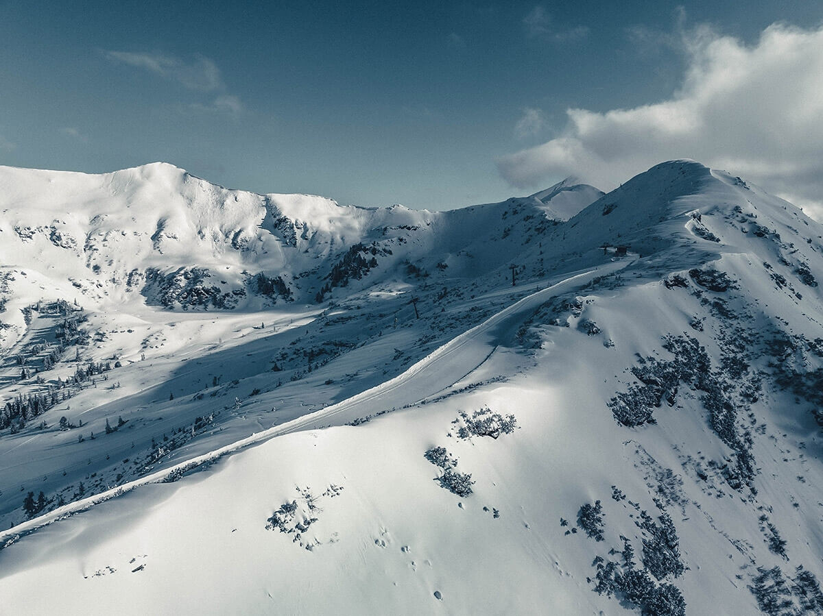 Winter landscape at the Planneralm ski resort in Austria, featuring snowy slopes, a mountain backdrop and a chalet, perfect for winter sports.