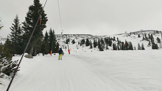 Skier heading downhill at the Planneralm ski resort in Styria, Austria, with a ski lift and chalet in the backdrop, creating a lively winter sports scene.