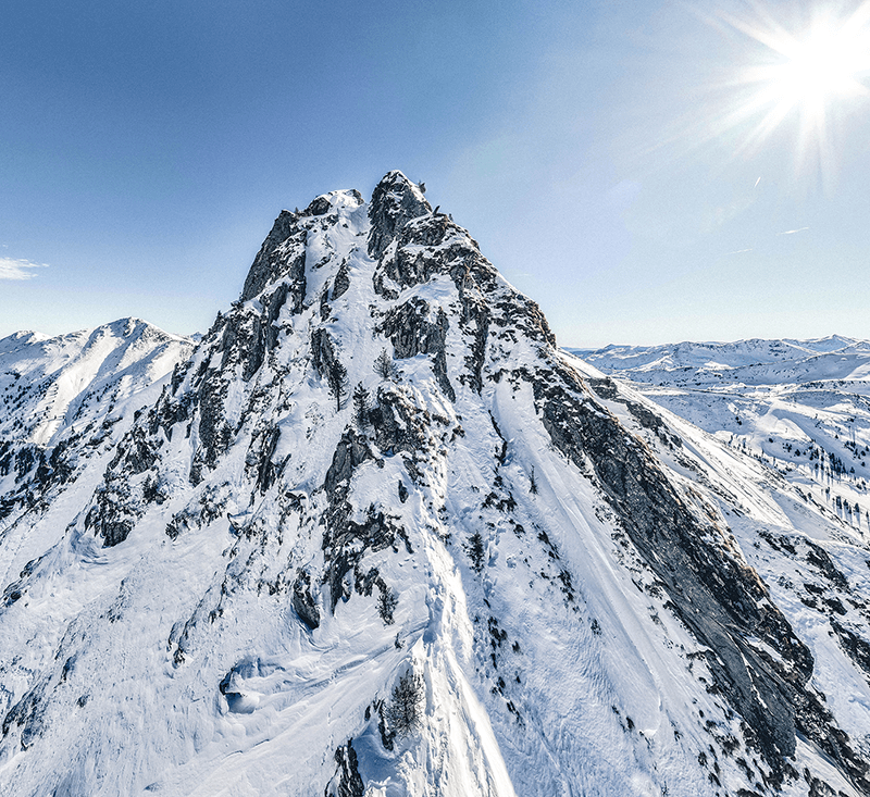 Scenic view of the Planneralm mountain range in Styria, Austria. The snow-covered peaks glow in the sunlight, offering an idyllic backdrop for winter sports. Skiers can be seen in the foreground, making their way down the slopes of the popular ski resort.