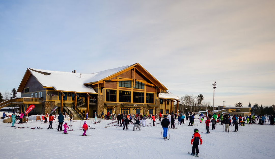 A winter sports scene at Giants Ridge in Biwabik Minnesota featuring a bustling ski resort with a ski lift and a cozy chalet nestled amidst snow-covered slopes.