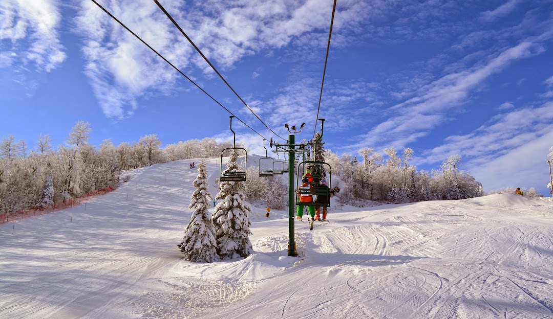 Ski lift at Giants Ridge, Biwabik, Minnesota transporting skiers amidst a picturesque winter scene. Ski resort and skiers are also visible, demonstrating winter sports activities.