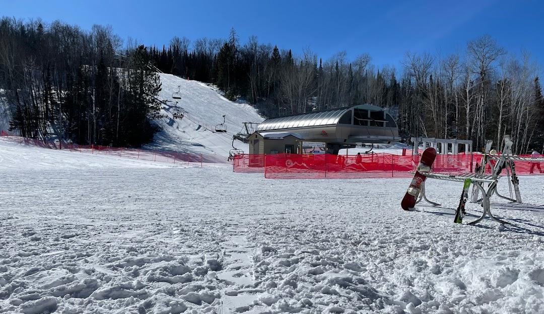 A skier descending the gleaming slopes at Giants Ridge ski resort in Biwabik Minnesota with a ski lift in the backdrop. The whole area is blanketed in fresh winter snow presenting an ideal winter sports scene.