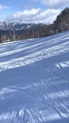 A skier descends the snow-covered slopes at Yabuhara Kogen, a popular ski resort in Nagano, Japan. A chalet is nestled in the background, completing the winter sports scene.