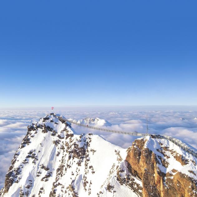 A scenic winter view at Les Mosses - La Lécherette in Switzerland, featuring a chalet nestled against a snow-covered mountain backdrop, with an active skier enjoying the winter sports scene.
