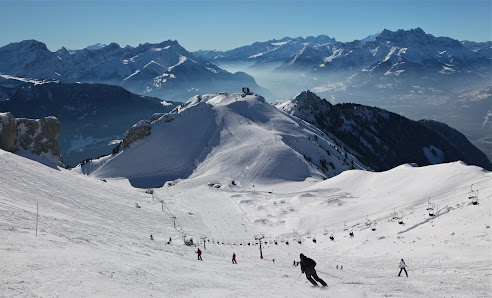 Winter scene at Les Mosses - La Lécherette ski resort in Switzerland, featuring a skier on the slope, a characteristic chalet, and the bustling winter sports centre.