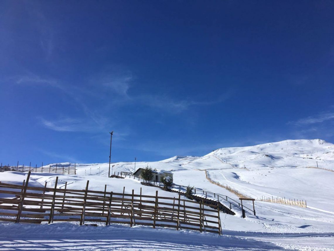 Chapa Verde in Chile - a wooden fence in the snow with mountains in the background.
