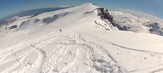 A skier is enjoying a winter sport scene in Chapa Verde Chile. They're moving down a snowy mountain slope. In the backdrop a charming chalet nested against the cold mountain range