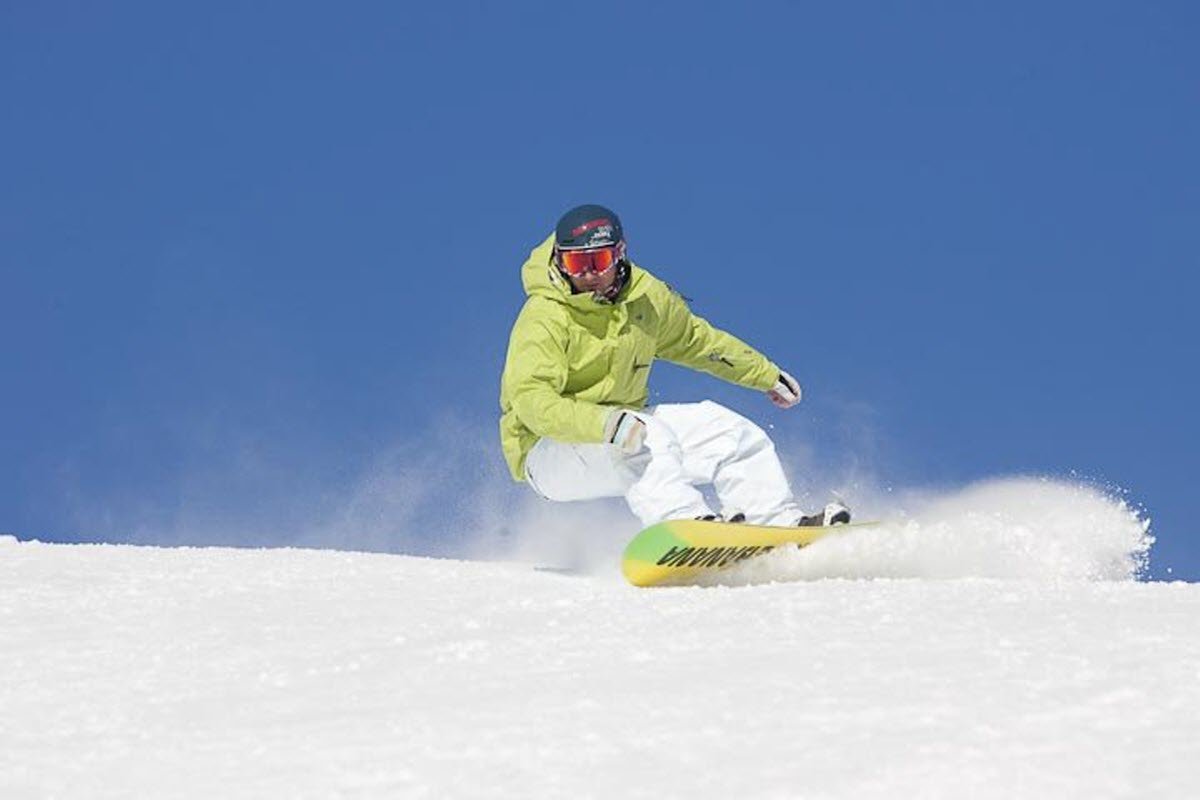 Mont Béchervaise in Canada - a man riding a snowboard down a snow covered slope.