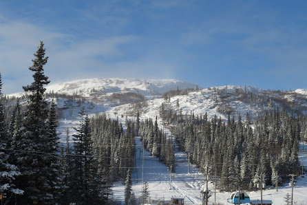 A ski resort in Smokey Mountain, Labrador City, featuring a ski lift, snow-covered slopes, and skiers partaking in winter sports activities.