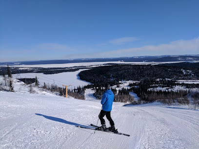 A skier enjoys the winter scene at Smokey Mountain Ski Resort in Labrador City Canada. The ski lift and a beautiful mountain are visibly part of the scenery.