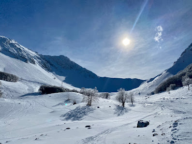 Winter panorama at Campo Stella in Leonessa, Italy, showcasing stunning wintry scenery. Skiiers enjoying winter sports in the snow-covered landscape with a charming chalet and a scenic mountain in the background.