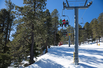 Ski lift operating amidst a winter sports scene at Sipapu Ski Resort in Vadito, New Mexico, with skiers and snowboarders enjoying the snowy slopes.