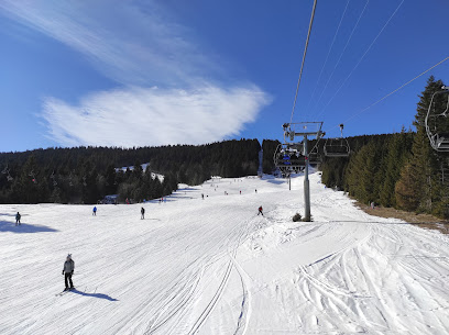 A winter scene at Adria Ski - Kupres in Bosnia and Herzegovina featuring a ski lift amongst snow-covered slopes a chalet and a bustling ski resort filled with winter sports enthusiasts.