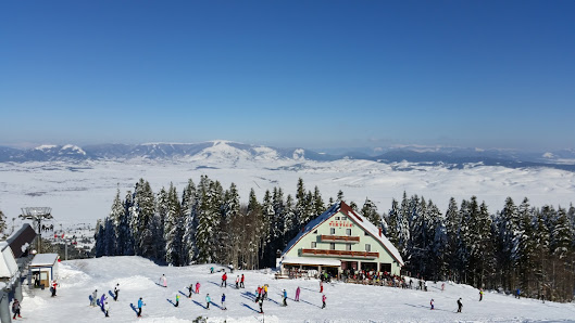View of Adria Ski – Kupres in Bosnia and Herzegovina featuring a bustling ski resort amidst a striking winter landscape. Visible elements include winter sports activities and a ski lift.