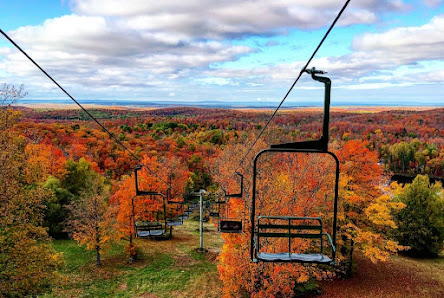 Ski lift scaling the snowy slopes of Whitecap Mountains in Upson Wisconsin revealing a lively winter sports scene featuring a Skier and a chalet nestled in the distance.