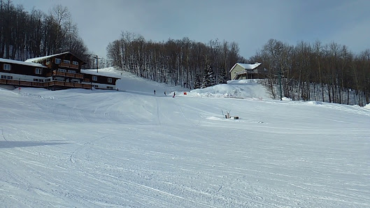 Winter sports enthusiasts enjoying the snow-covered slopes at Whitecap Mountains Ski Resort in Upson, Wisconsin, USA, with a chalet and ski lift visible in the distance.