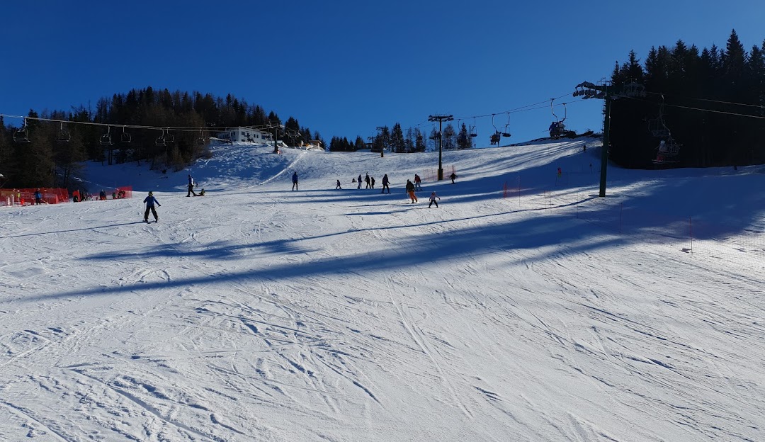 Winter sports scene at Panarotta 2002 in Trentino, featuring a skier on the snowy slopes. A charming chalet and ski resort form a picturesque background.