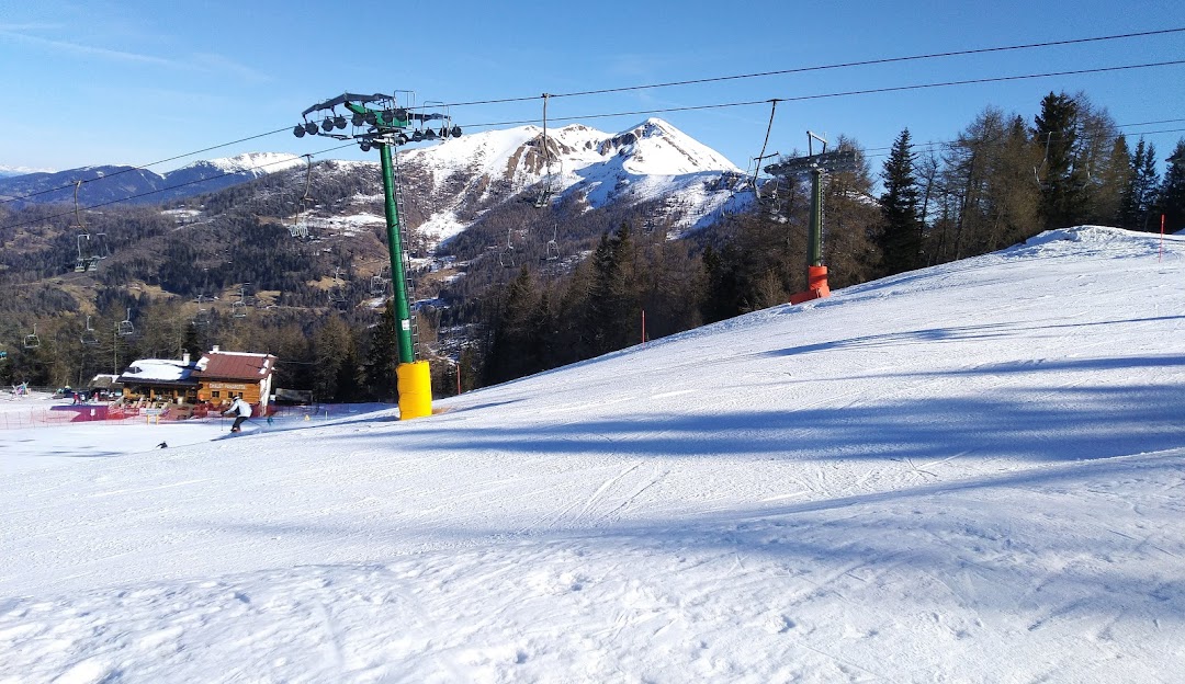 A charming chalet amidst a bustling ski resort at Panarotta 2002 in Italy. Winter sports enthusiasts can be seen enjoying the snowy slopes, with a ski lift enhancing the alpine experience.