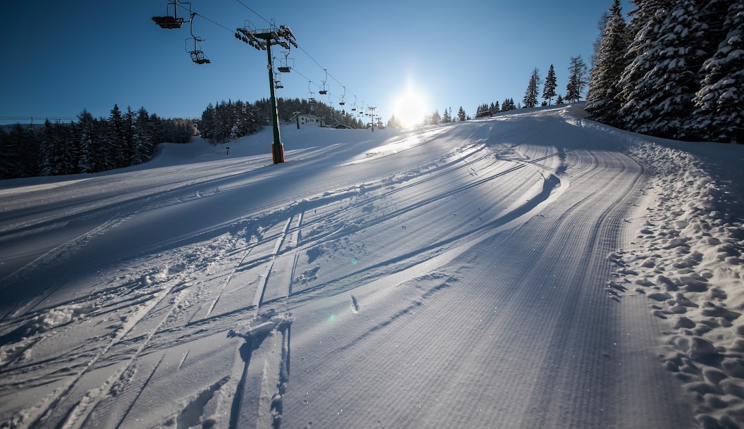 Ski scene at Panarotta 2002 in Trentino, Italy. A skier maneuvers down a snowy slope with a ski lift nearby, and a challet tucked amidst the snow-covered landscape.