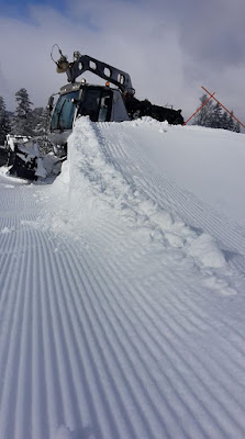 A skier races down a slope at Bugnenets - Savagnières ski resort in Switzerland framed by a ski lift and a charming chalet with a snowmobile nearby.