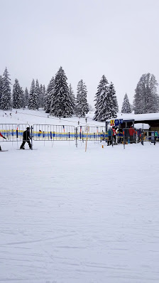 Winter sports scene at Bugnenets - Savagnières in Switzerland featuring a busy sports centre a ski resort and a ski lift against beautiful winter scenery.